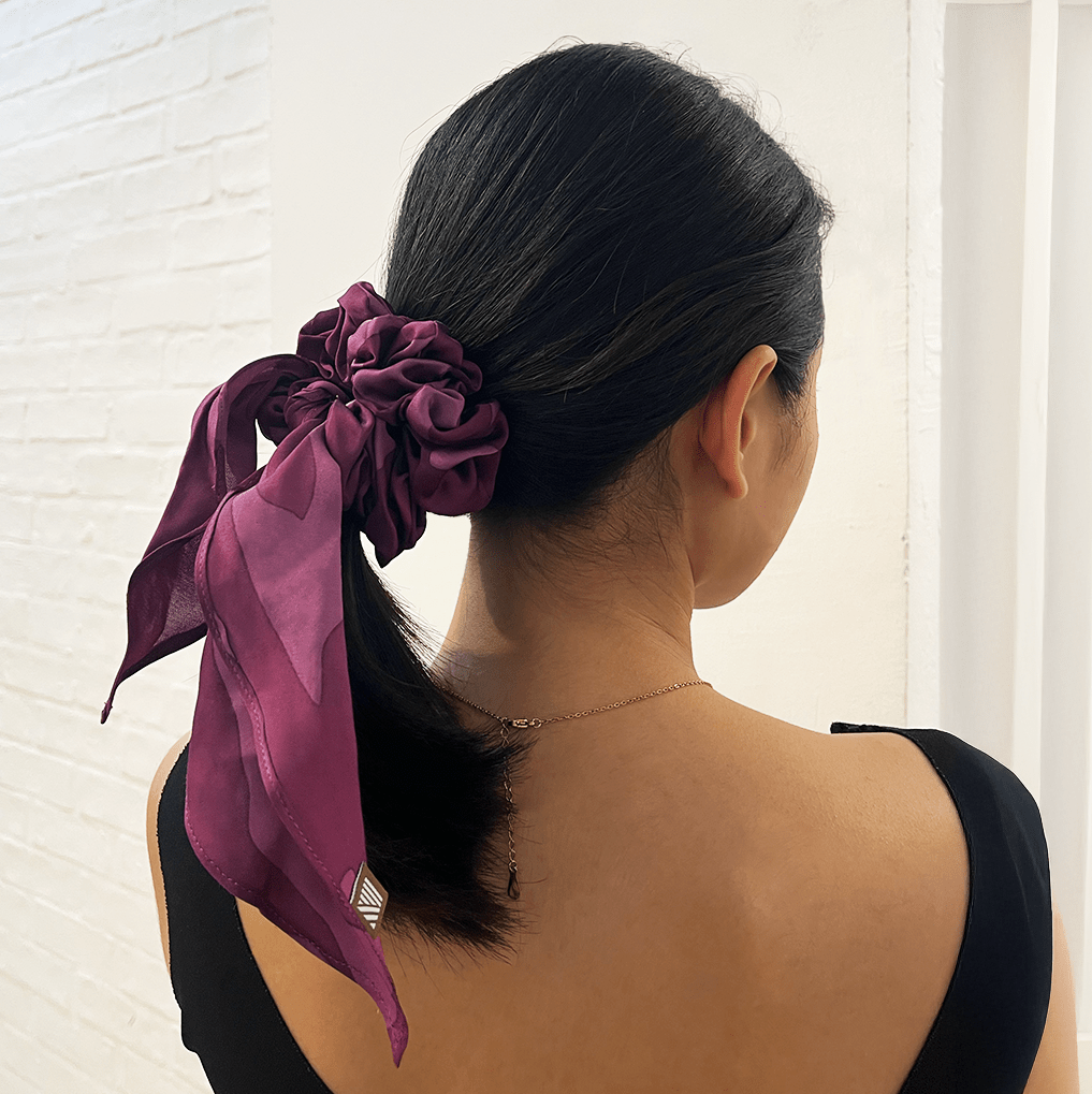 Woman wearing Plum Rimba batik scrunchie with ribbon tail.