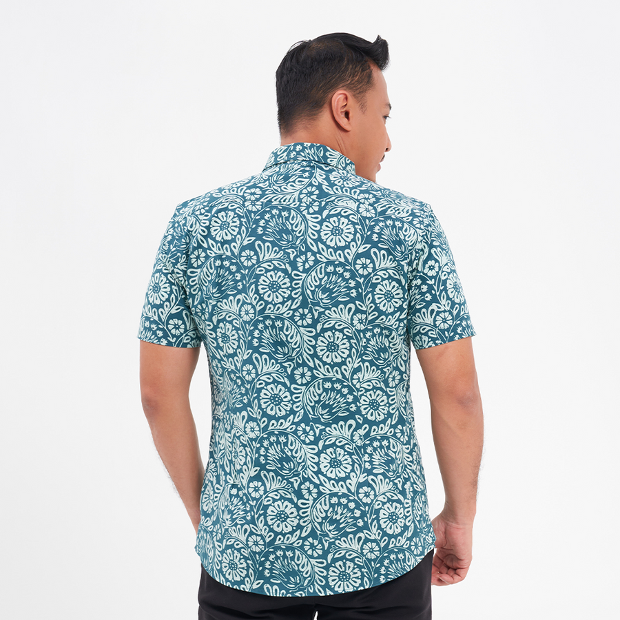 a male model facing away from the camera to highlight the back of the batik shirt in the pattern teal ukir