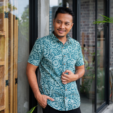 a male model posing in a batik shirt in the pattern teal ukir in a lifestyle photo