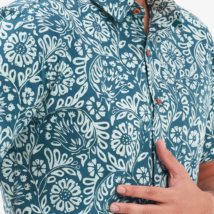 a closeup shot of a male model wearing a batik shirt in the pattern teal ukir