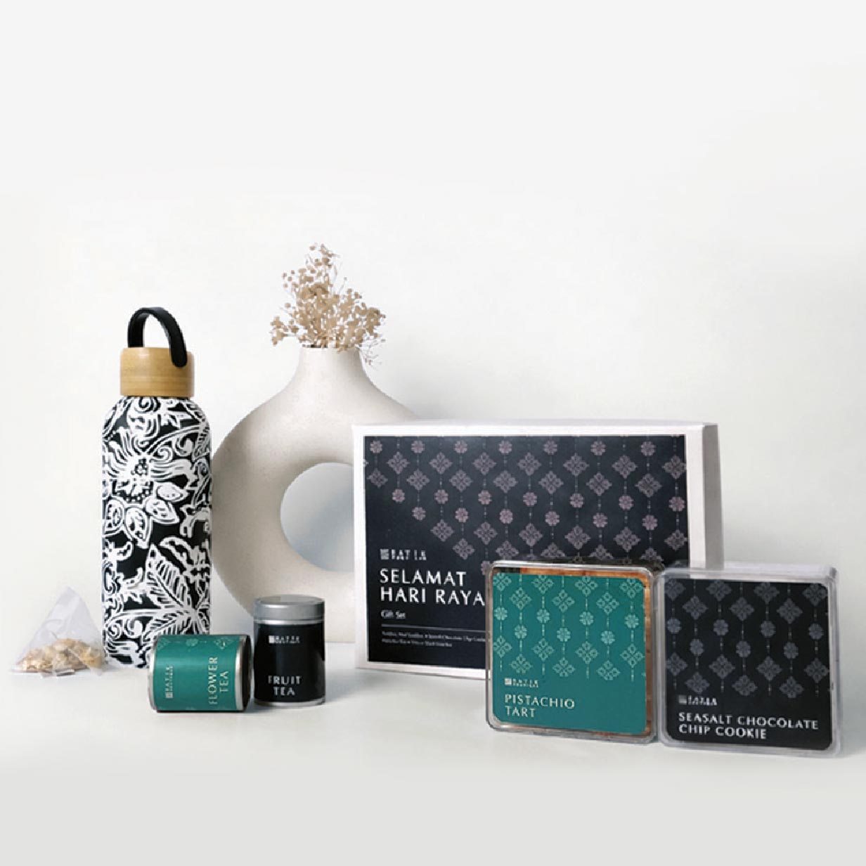 Collection of tea packaging and decorative items on a white surface with a light gray background.