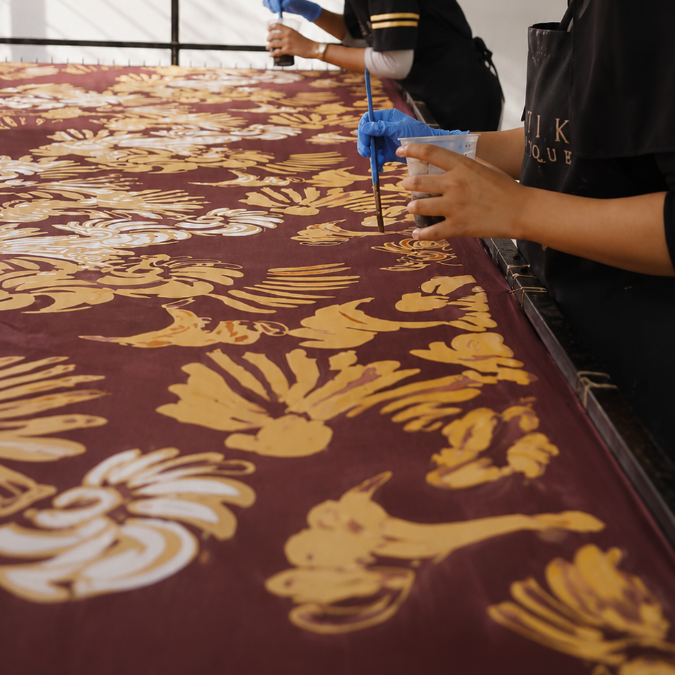 Hands wearing blue gloves holding a brush over a patterned surface
