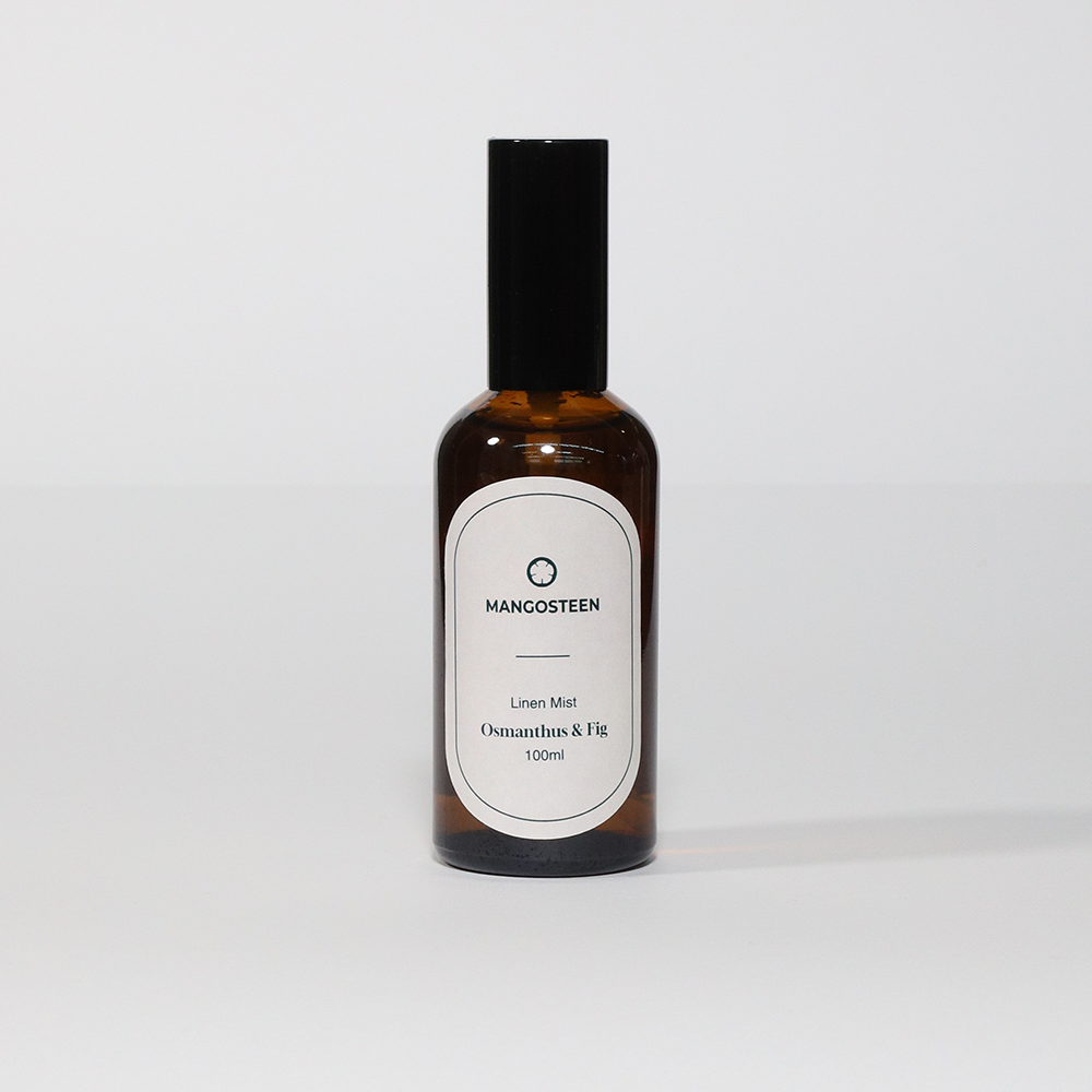 A brown bottle of Linen Mist with a white label that reads 'Mangosteen Linen Mist Osmanthus & Fig 100ml'.