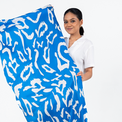 Model holding Batik Boutique’s Blue Rimba scarf, showcasing its bold hand-drawn batik pattern in vibrant blue and white