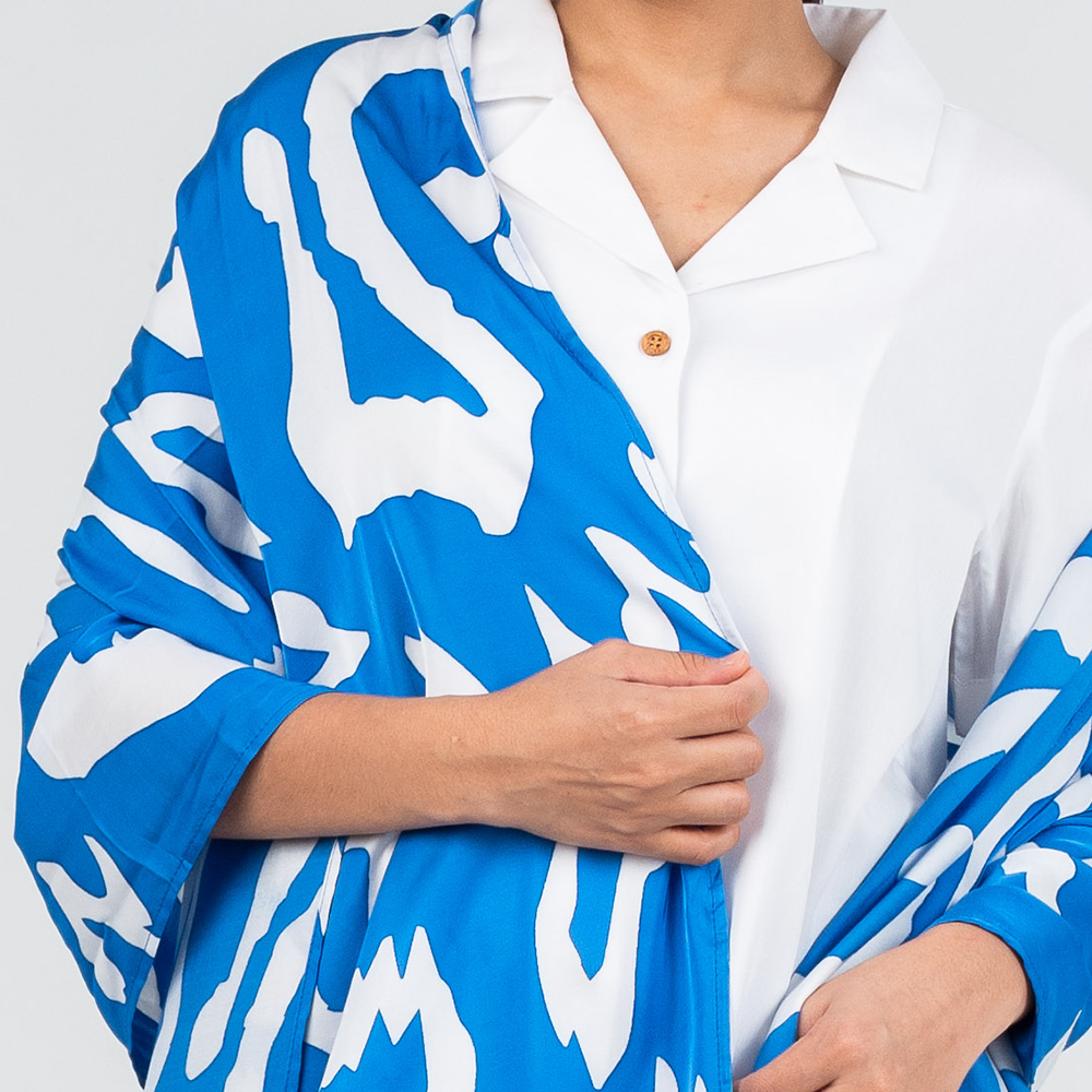 women wearing the blue rimba scarf around her body showing the bright blue and white pattern 