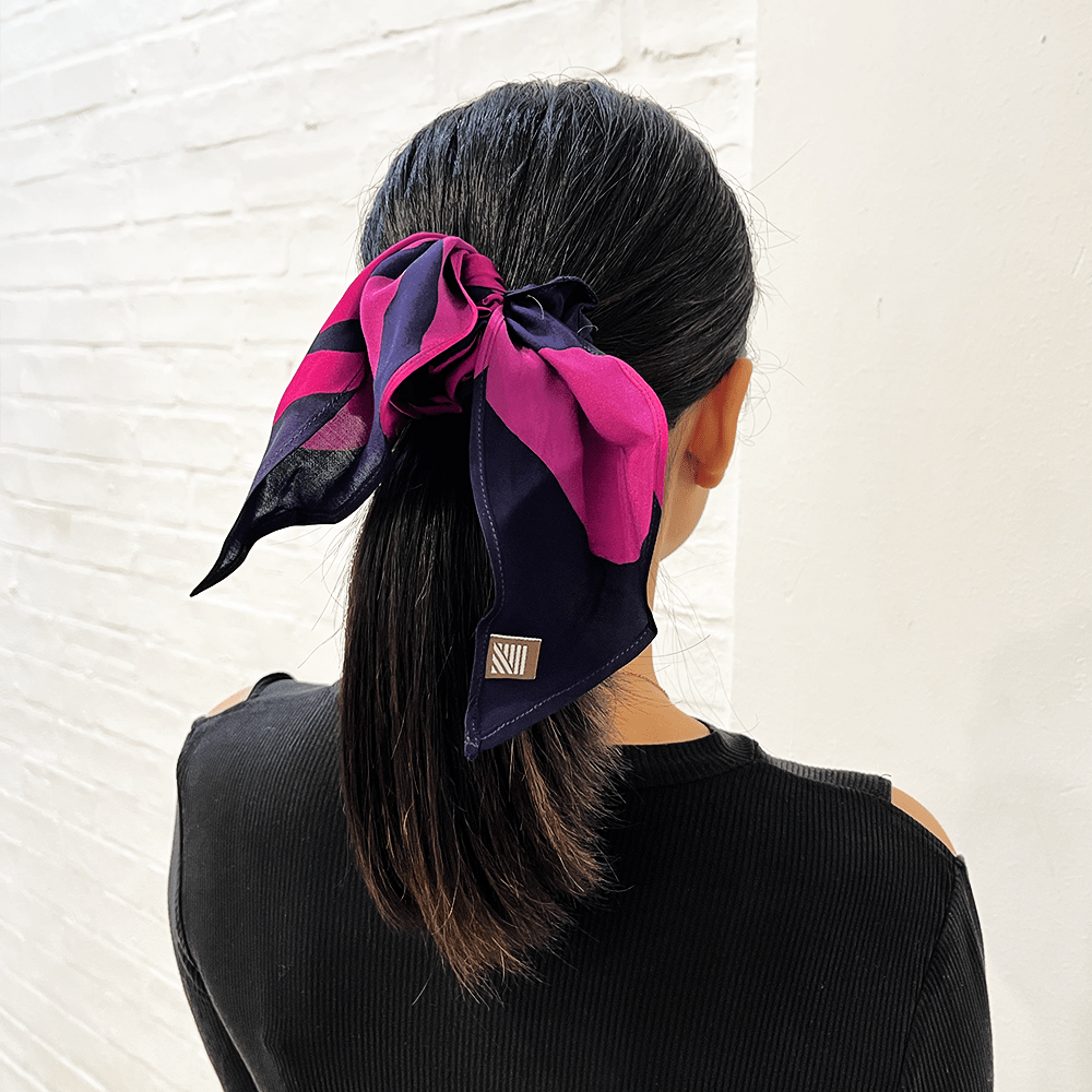 Person wearing a pink and black scarf tied around their head against a white background
