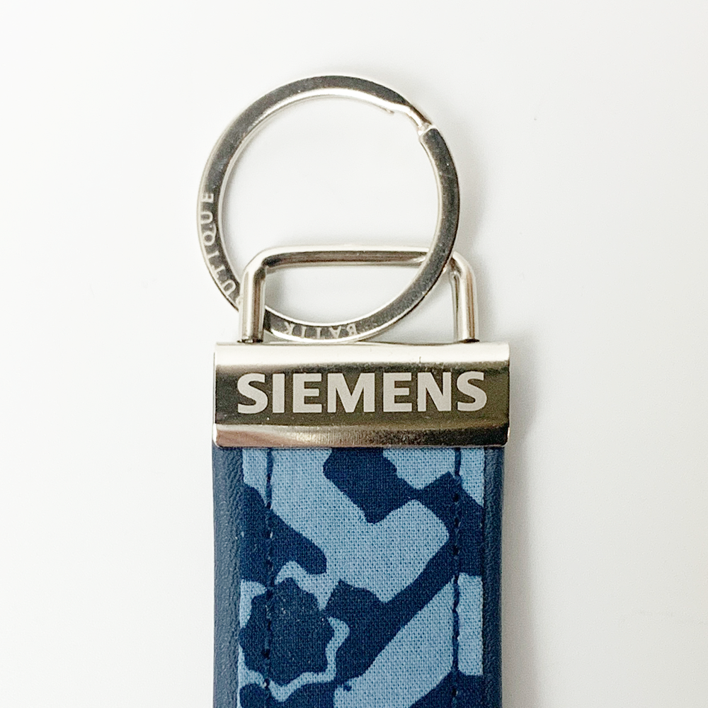 Keychain with Siemens logo on a blue camouflage strap against a white background