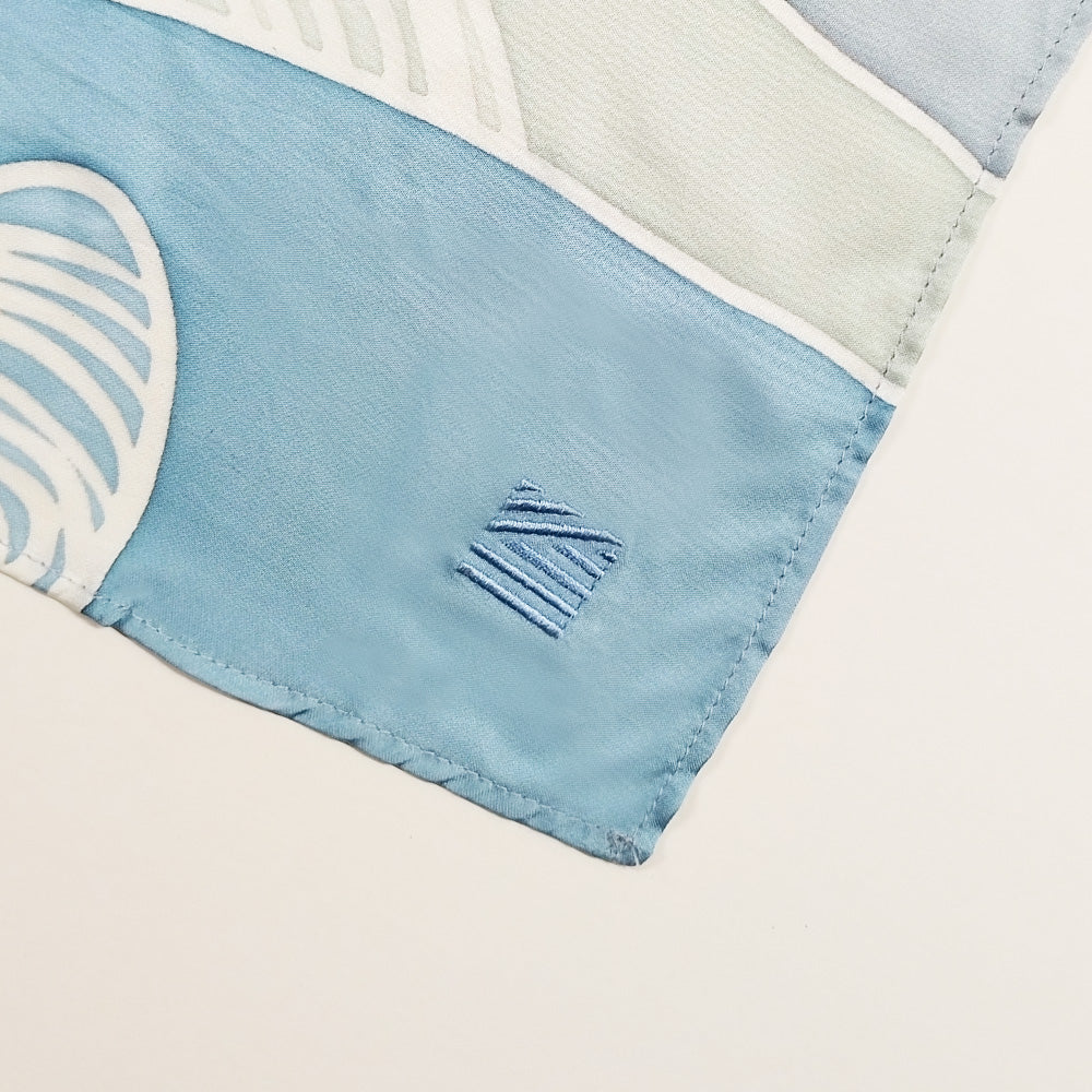 A close-up shot emphasizing the intricate embroidery of the logo on the batik scarf