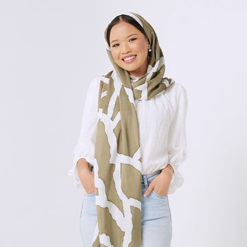  a woman standing in front of white background styling batik scarf in stone chain pattern