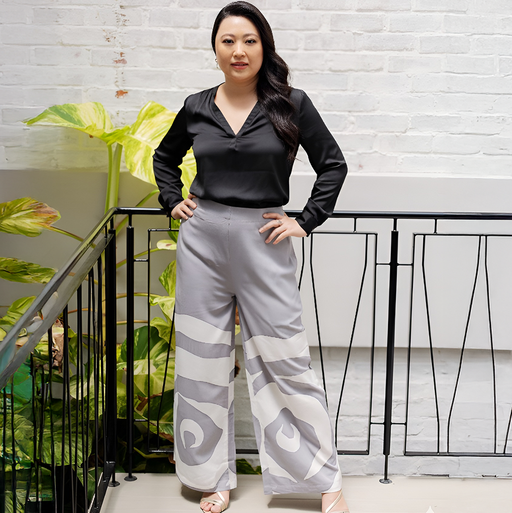 Woman wearing a black top and patterned gray pants standing against a white brick wall.
SilverRoseTrouser