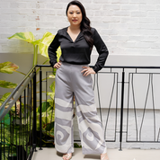 Woman wearing a black top and patterned gray pants standing against a white brick wall.
SilverRoseTrouser
