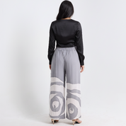 Person wearing a black top and gray patterned pants on a white background