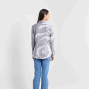 Woman wearing a gray patterned sweater and blue jeans on a white background