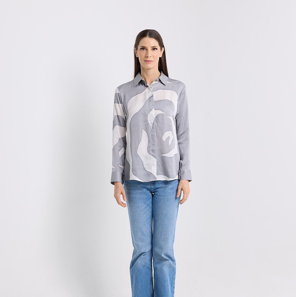 Woman wearing a gray patterned shirt and blue jeans on a white background