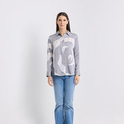 Woman wearing a gray patterned shirt and blue jeans on a white background