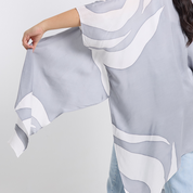 Gray and white patterned fabric being held against a light gray background. 