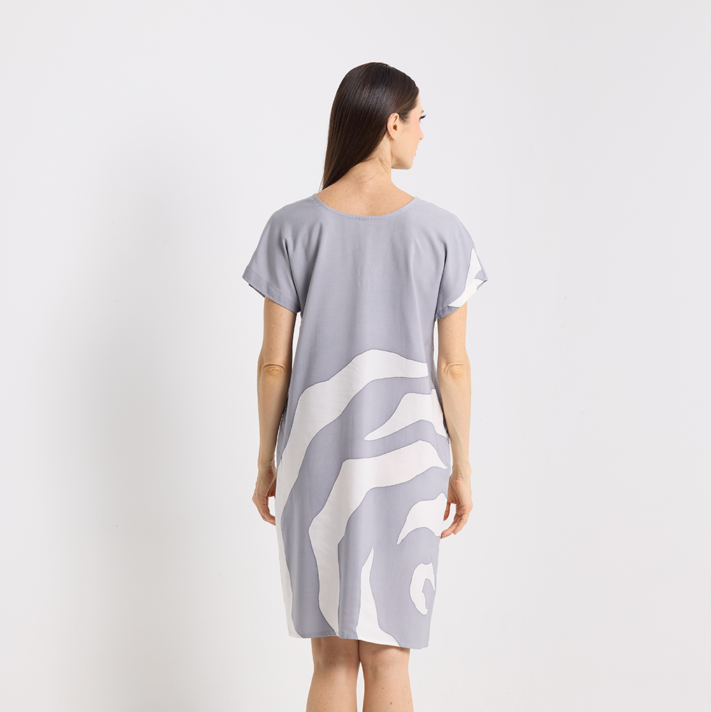 Woman wearing a gray dress with white abstract pattern on a white background