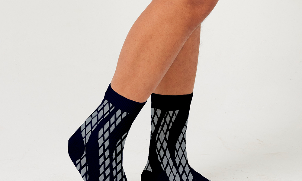 a model wearing a new pattern black snakeskin socks against a white background