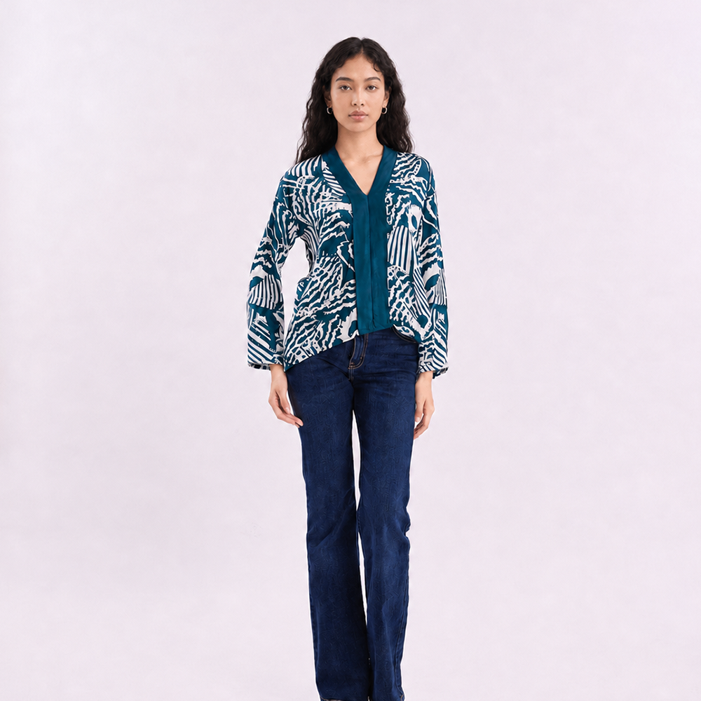 A woman wearing a blue kebaya top with a blue shell pattern, on a white background.