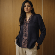 Woman wearing a black blazer over a patterned shirt against a wooden background
