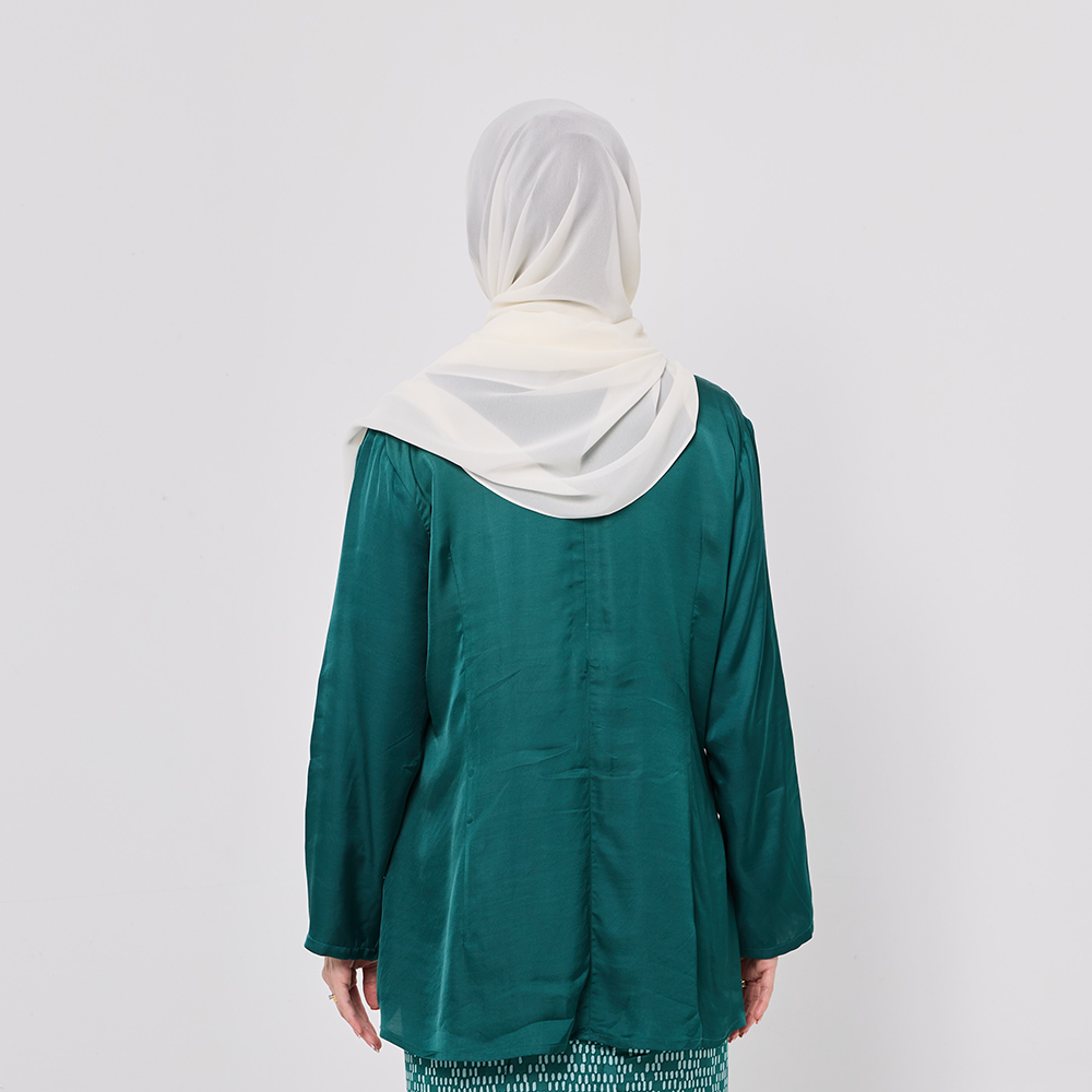 Person wearing a green top and white hijab on a plain background