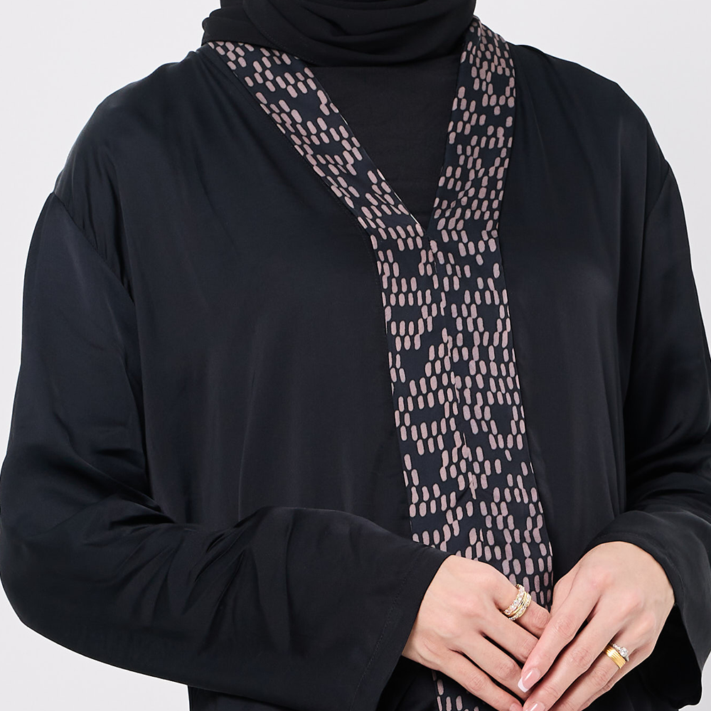 Person wearing a black outfit with a patterned scarf on a white background