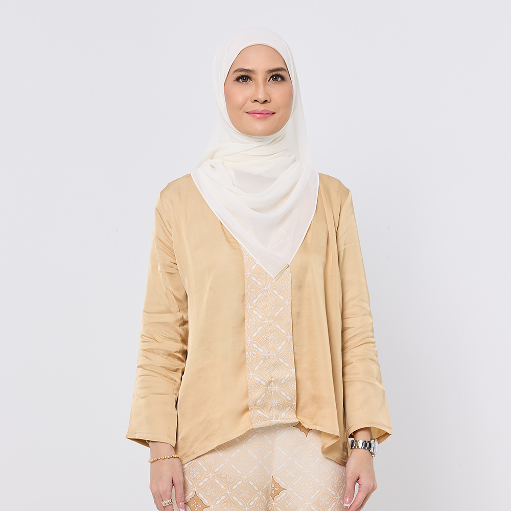Woman wearing a beige outfit with a white hijab on a plain background
