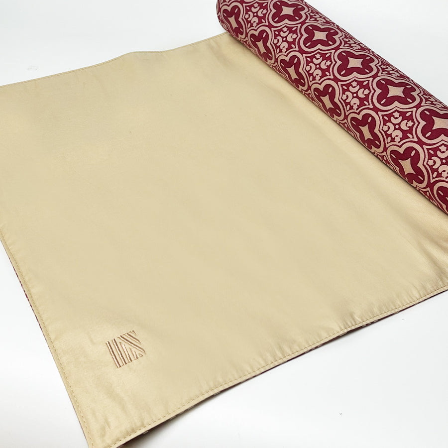 A roll up photo of table runner in crimson celestial with batik boutique logo embroided