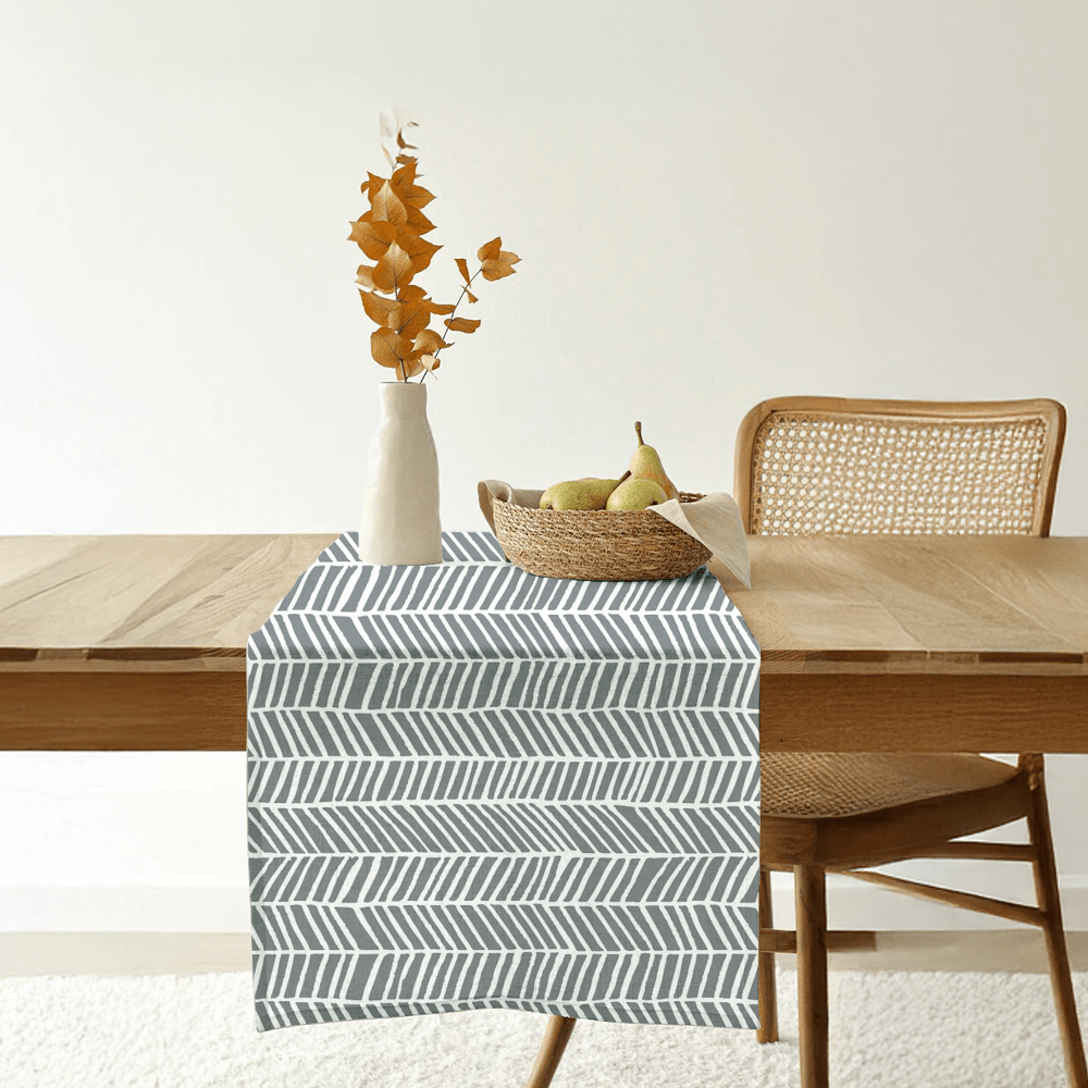 Grey batik table runner with banana leaf pattern styled on a wooden dining table.