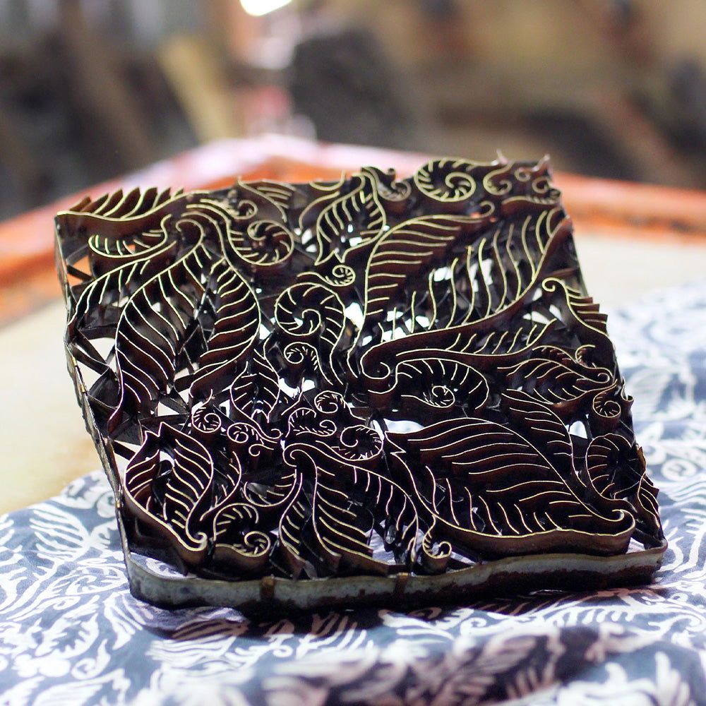 Decorative wooden block with intricate leaf patterns on a table.