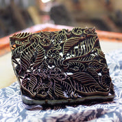 Decorative wooden block with intricate leaf patterns on a table.