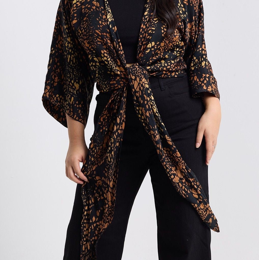 Person wearing a leopard print kimono over a black outfit on a white background