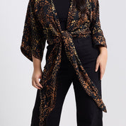 Person wearing a leopard print kimono over a black outfit on a white background