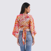 Woman wearing a colorful kimono-style top with a plain background