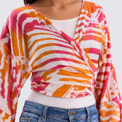 Colorful patterned cardigan over a white shirt and blue jeans on a plain background