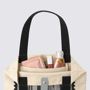 Closeup of totebag with gray-ish KL inspired prints, and products inside