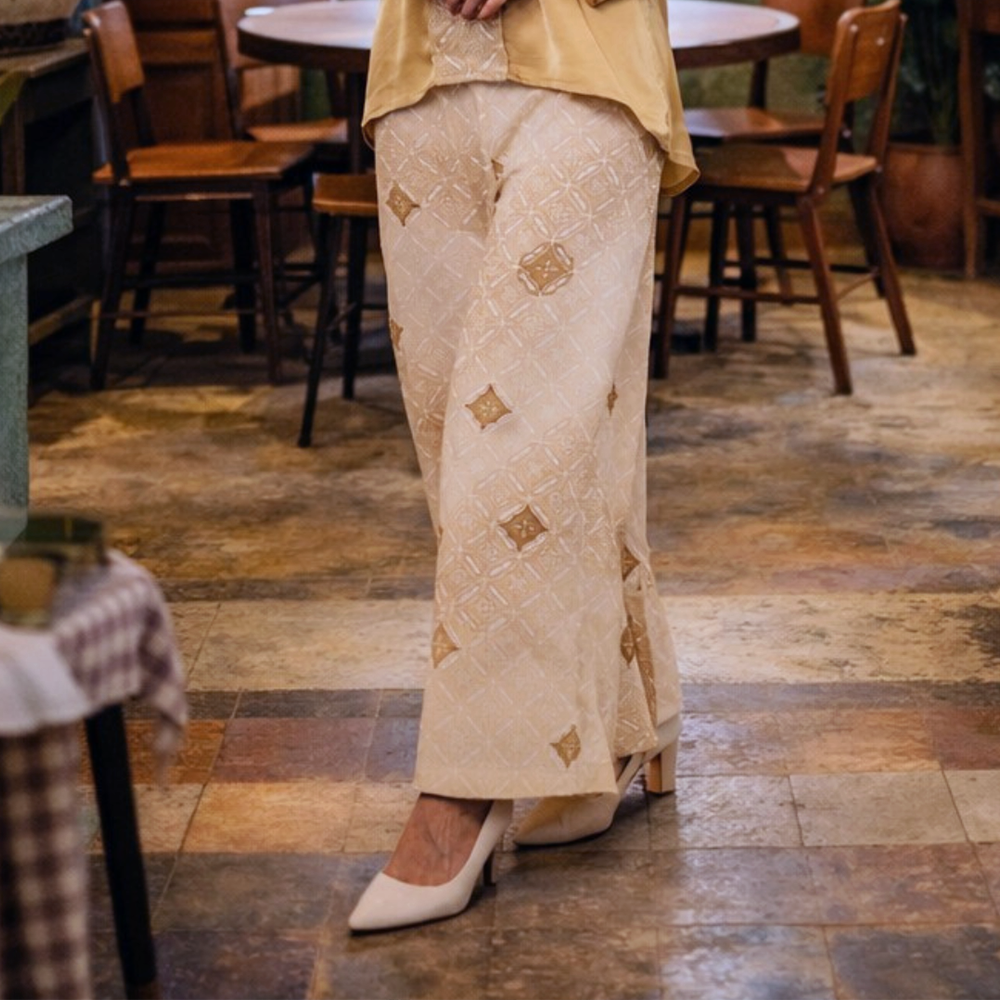 Person wearing a traditional outfit with embroidered pants in a casual setting.