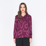 a woman posing in a batik shirt in the pattern plum rimba against a white background