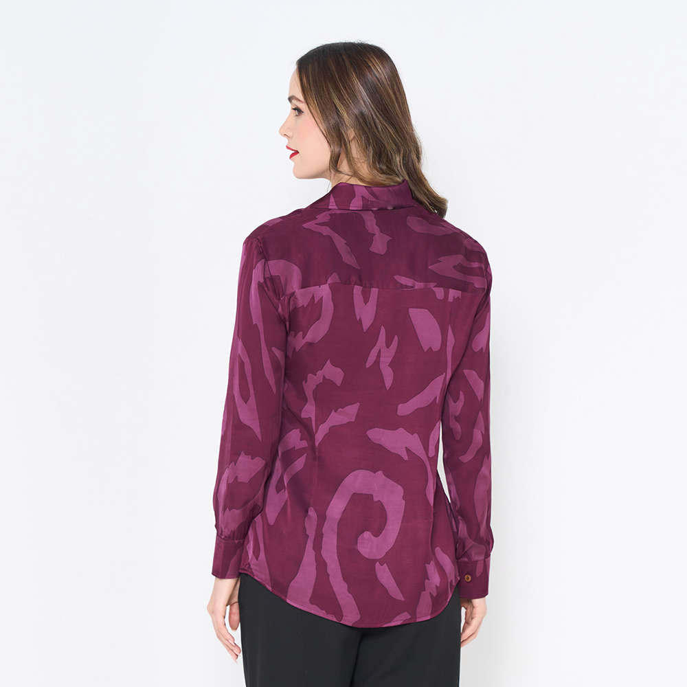 a woman showcasing the back of batik shirt in the pattern plum rimba against a white background