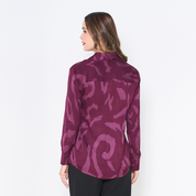 a woman showcasing the back of batik shirt in the pattern plum rimba against a white background