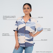 Woman wearing a patterned shirt with text describing its features on a light gray background