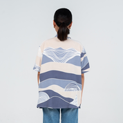 Person wearing a patterned shirt with wavy design on a plain background