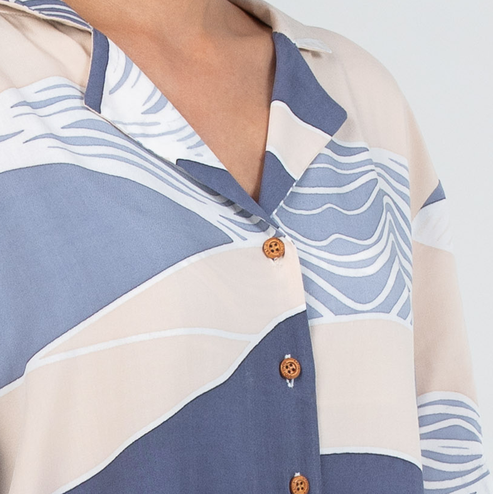 Close-up of a patterned shirt with blue and beige design on a white background