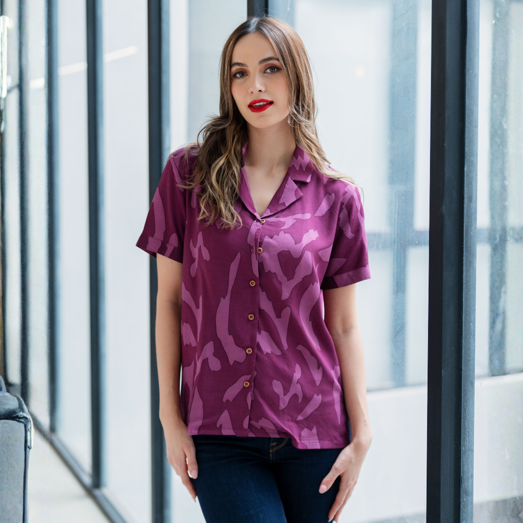 Woman wearing a purple patterned shirt standing in a modern indoor setting.