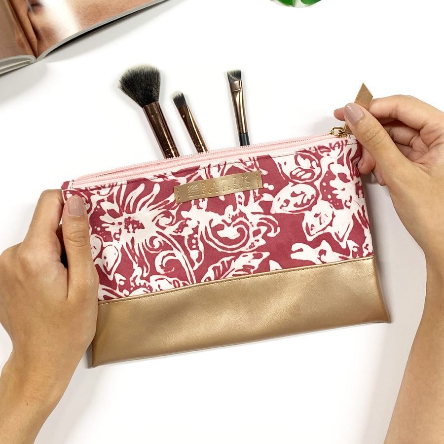 a lifestyle photo of women hand holding batik zip pouch in pink floret