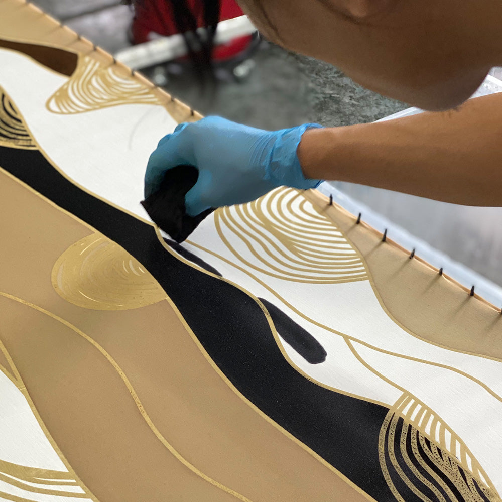 an artisan is hand painting fabric of batik in bukit print