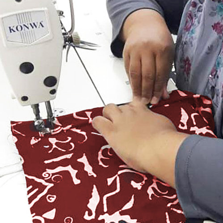 A seamstress is sewing red color batik fabric in crimson diwanie pattern
