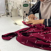 A seamstress is sewing batik fabric in crimson tangga pattern, sewed into batik dress