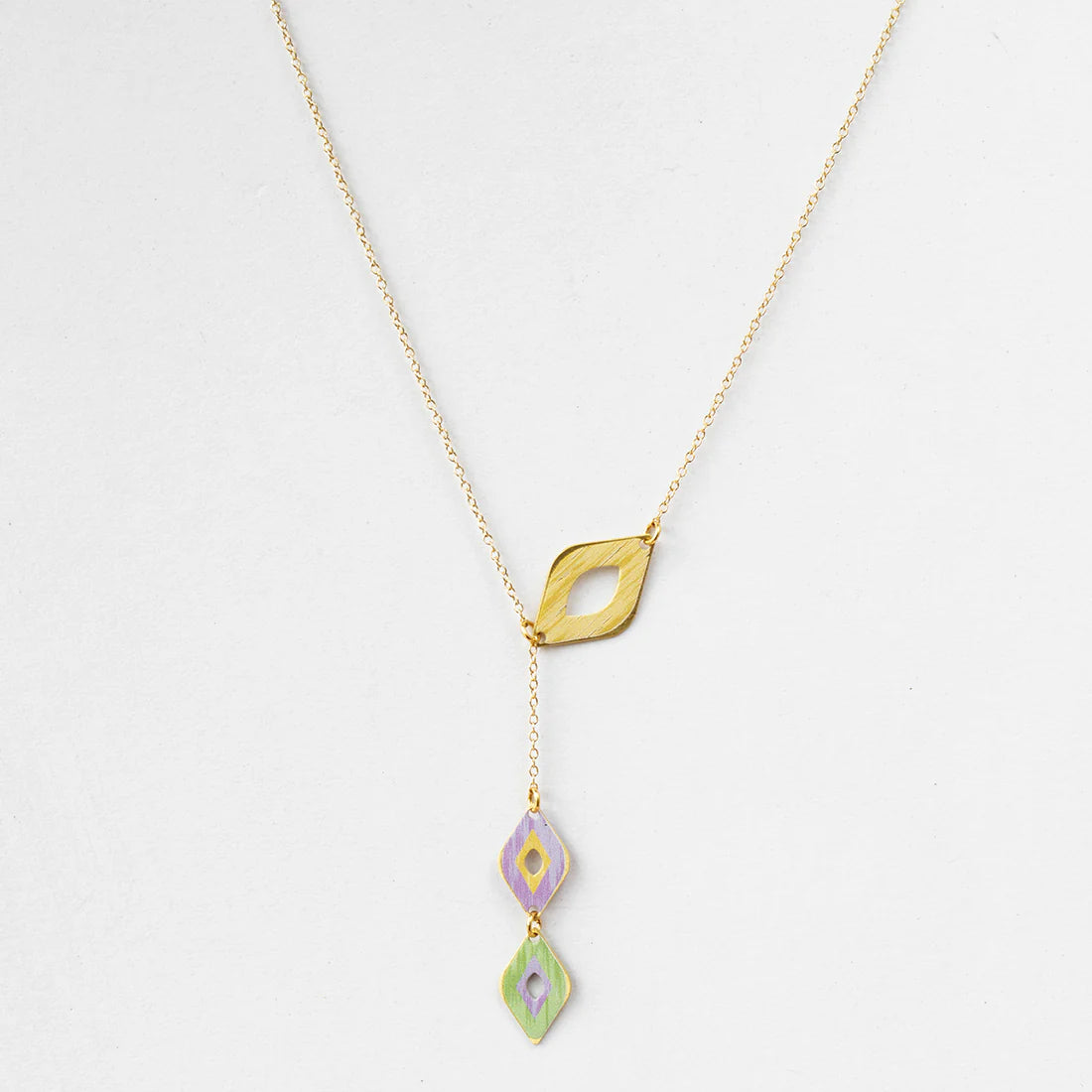 Gold necklace with three colorful pendant drops on a light gray background