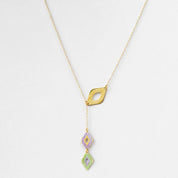 Gold necklace with three colorful pendant drops on a light gray background
